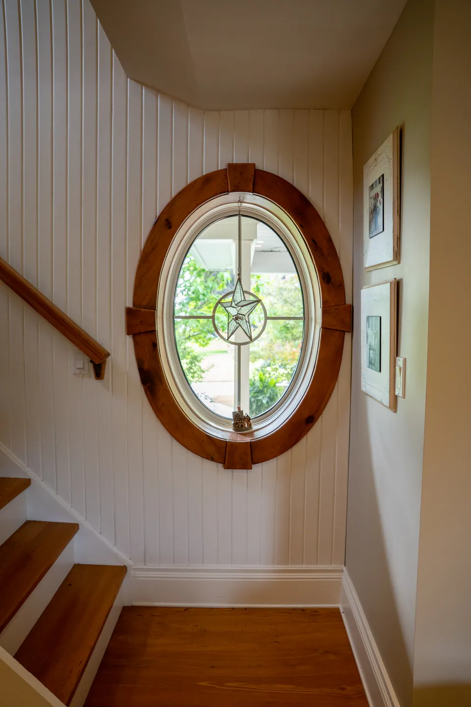 Round leaded-glass window beside the timber staircase