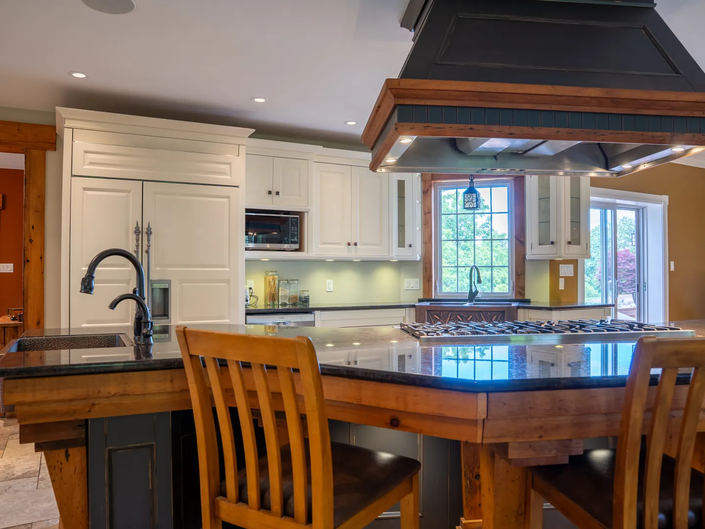 Kitchen island with a dark stone counter and wooden bar stools