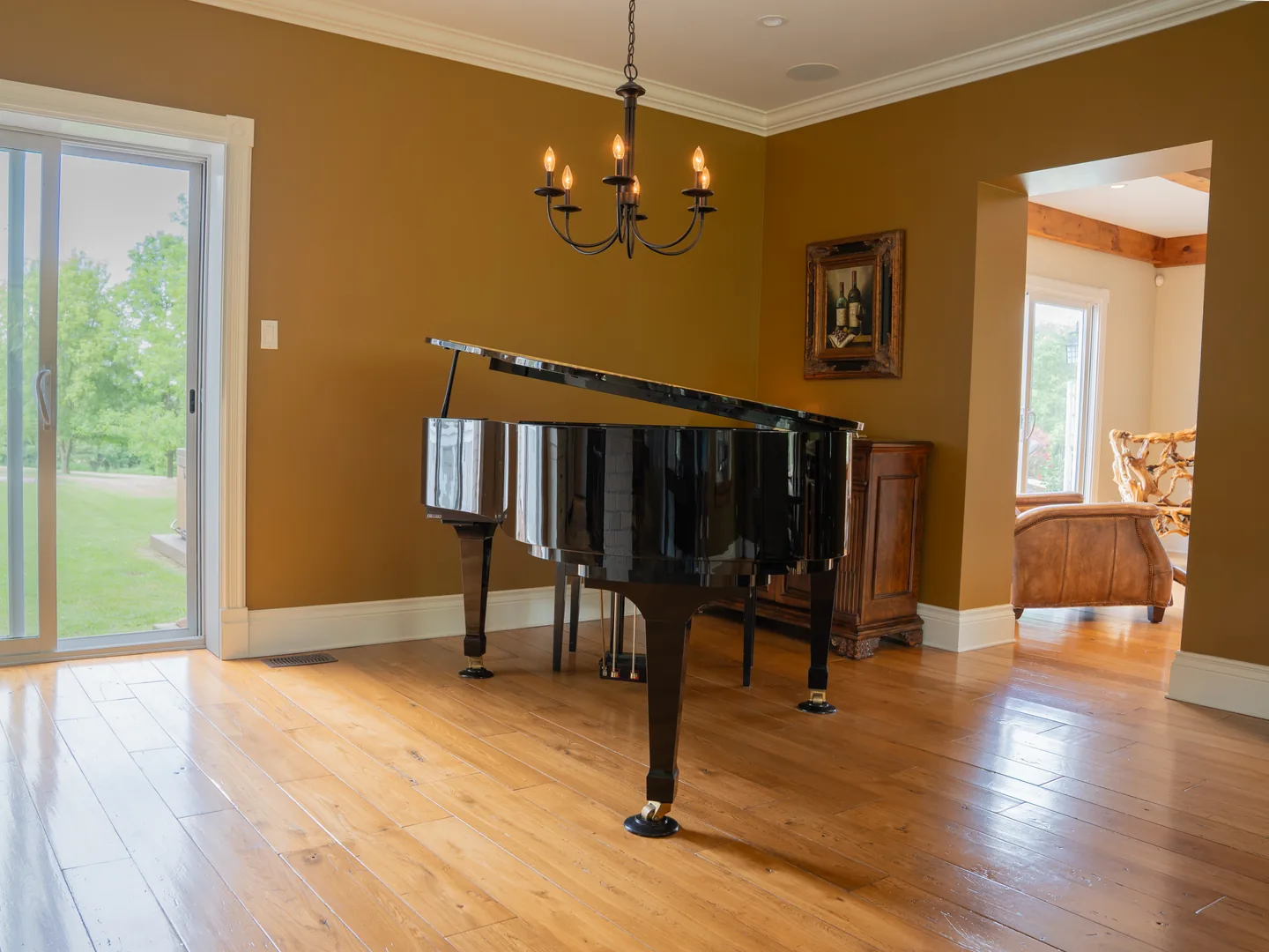 Grand piano on wide-plank oak beneath an iron chandelier