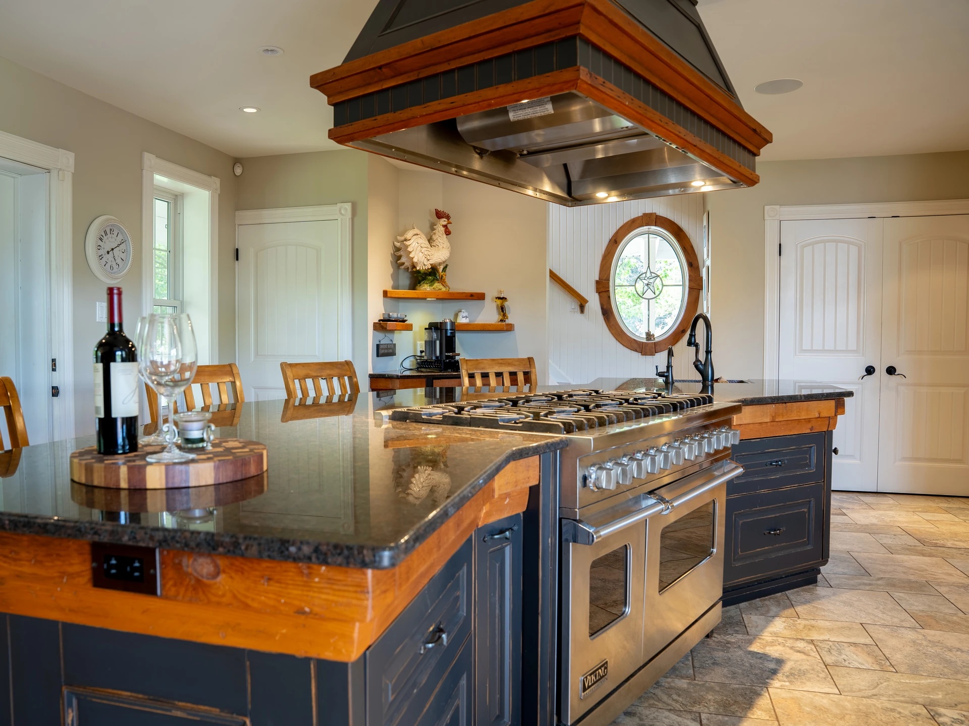 Kitchen island and range viewed from across the room, with the oval leaded-glass window and stairwell visible beyond.