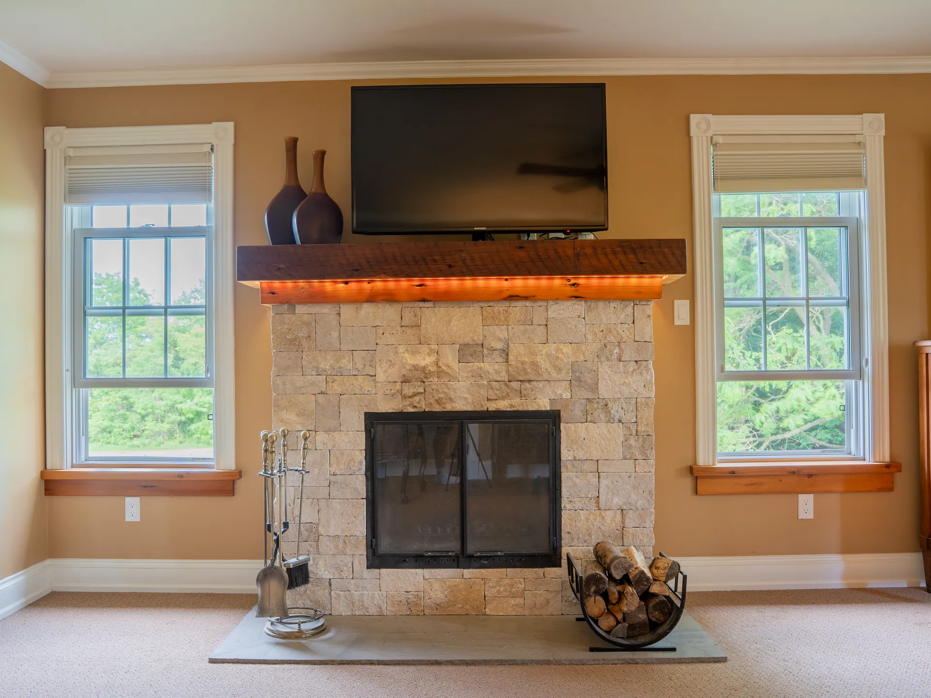 Bedroom with stone fireplace, television and windows